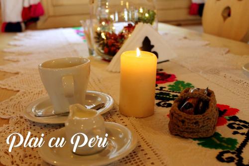 a table with a candle and a cup and a cake at "Plai cu Peri" in Săpînţa