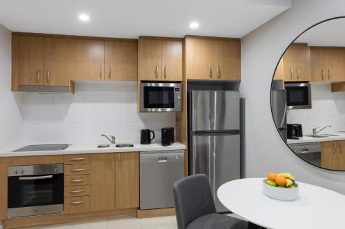 a kitchen with wooden cabinets and stainless steel appliances at Meriton Suites Waterloo in Sydney