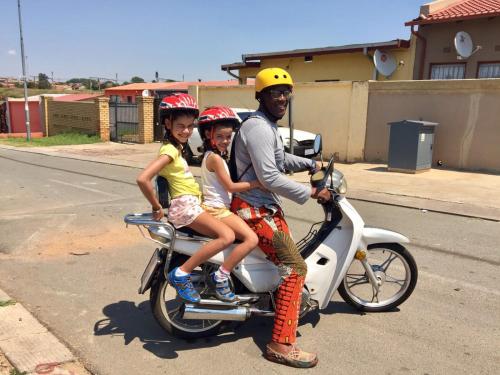 a man and two children riding on a scooter at Authentic Bicycle Tours and Backpackers in Soweto