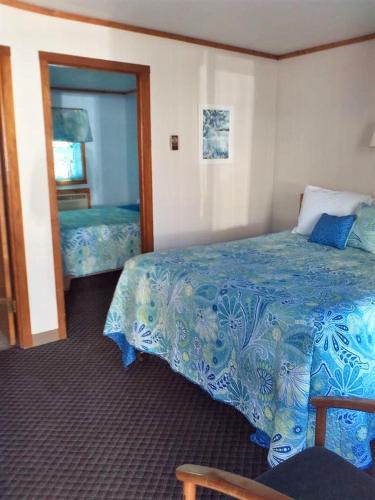 Habitación de hotel con cama y espejo en The Monarch Motel, en Cheboygan