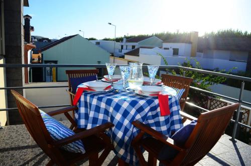 a table with plates and glasses on a balcony at Cabo da Vila Guesthouse in Ribeira Grande
