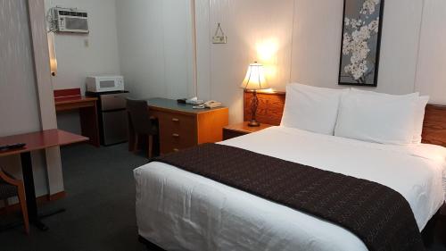 a hotel room with a bed and a desk at Red Coat Inn Motel in Fort Macleod