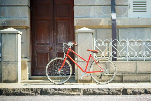 a red bike parked on a sidewalk in front of a door at ROUTE - Cafe and Petit Hostel in Nagasaki