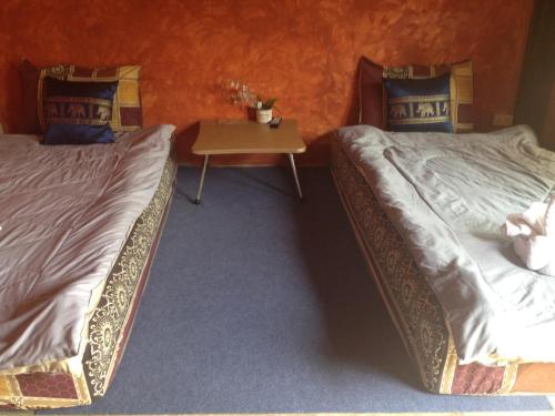 two beds in a room with a table between them at Milin Guesthouse in Chiang Rai