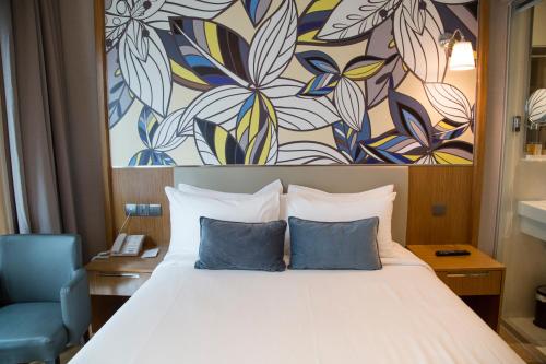 a bed with two blue pillows in a hotel room at Hotel Bencoolen at Hong Kong Street in Singapore