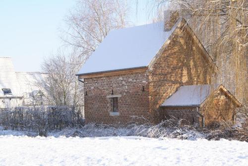 an old brick house with snow on the roof at B&B De Metstermolen in Sint-Truiden