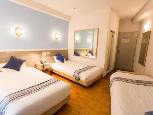 a hotel room with two beds and a mirror at Hotel AreaOne Sakaiminato Marina in Sakaiminato