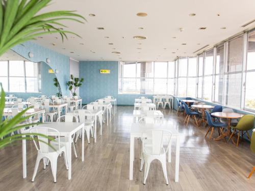 a restaurant with white tables and chairs and windows at Hotel AreaOne Sakaiminato Marina in Sakaiminato