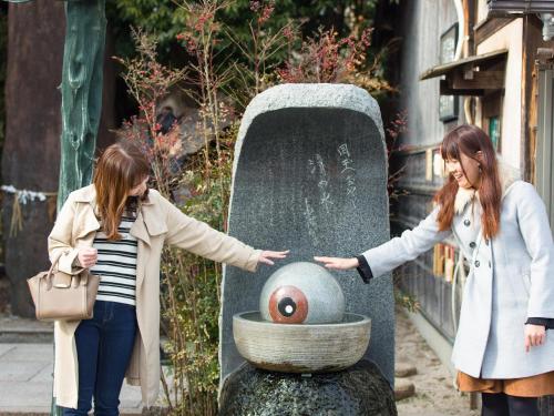 two girls are standing next to a monument with aeye at Hotel AreaOne Sakaiminato Marina in Sakaiminato
