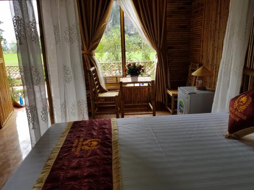 a bedroom with a bed and a window with a chair at Tam Coc Horizon Bungalow in Ninh Binh