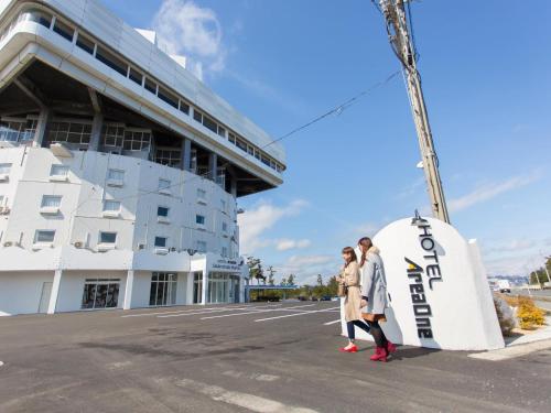 two people standing in front of a building at Hotel AreaOne Sakaiminato Marina in Sakaiminato