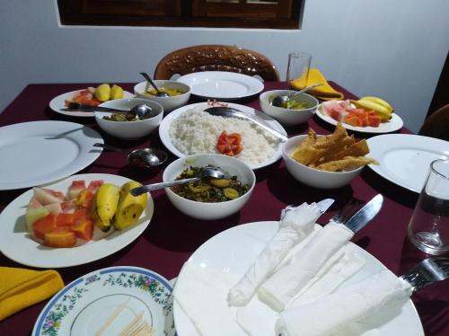 una mesa con platos blancos y tazones de comida en Nimsara Lodge Sigiriya en Sigiriya