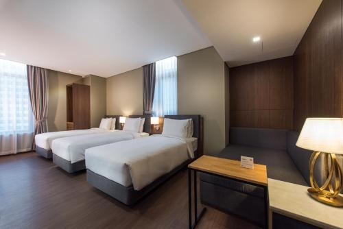 a hotel room with two beds and a couch at ENA Suite Hotel Namdaemun in Seoul