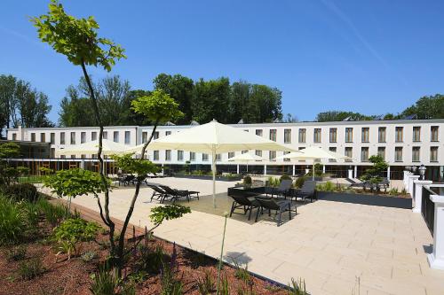 a courtyard with tables and umbrellas in front of a building at Schlosspark Mauerbach - Adults only in Mauerbach