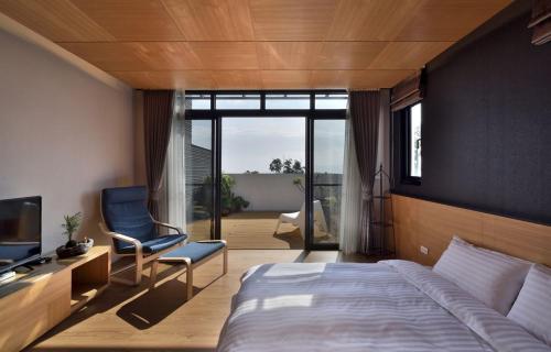 a bedroom with a bed and a tv and a chair at Shan Yi Fang Resort in Yuanshan