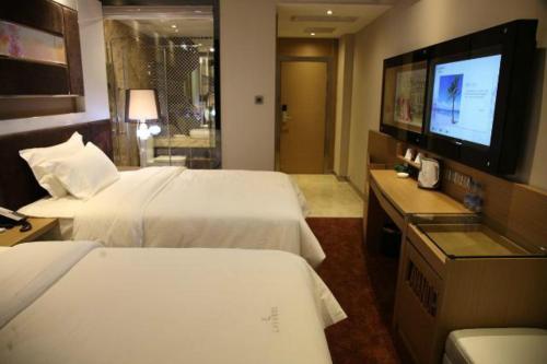 a hotel room with two beds and a flat screen tv at Lavande Hotel Zhuhai Gongbei Port Square in Zhuhai
