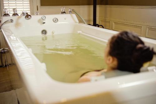 una donna seduta in una vasca da bagno piena d'acqua di Arcadia Hotel - Marina Regia Residence a Mamaia Nord - Năvodari