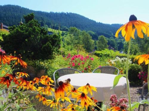 a table and chairs in a garden with flowers at Gästehaus Heimenberg in Bad Rippoldsau-Schapbach