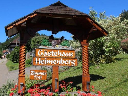 a wooden gazebo with a sign in a garden at Gästehaus Heimenberg in Bad Rippoldsau-Schapbach