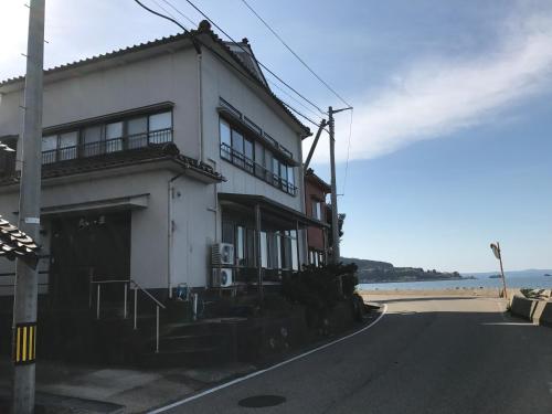 a white building on the side of a beach at Notojima Guesthouse HaNaMi in Nanao