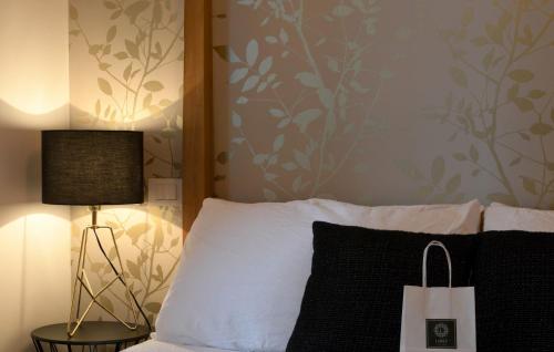 a bed with a black and white pillow and a lamp at Lainez Rooms & Suites in Trento
