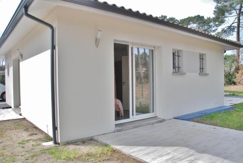 a white house with a large sliding door at Villa Donosti Chambres d'Hôtes in Lanton