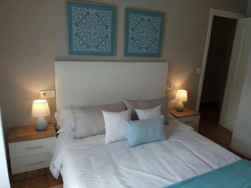 ビラガルシーア・デ・アロウサにあるAcogedor piso en el corazón de la ciudadのベッドルーム1室(白いベッド1台、壁に青い絵画付)