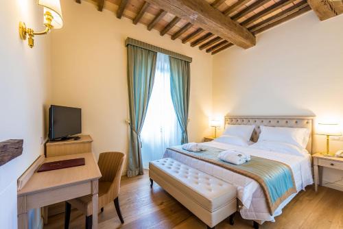 a bedroom with a bed and a desk and a television at Relais Paradiso Resort & Spa in Gualdo Cattaneo