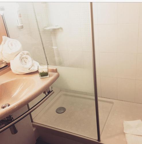 a bathroom with a shower and a sink and towels at ibis Rennes Cesson in Cesson-Sévigné