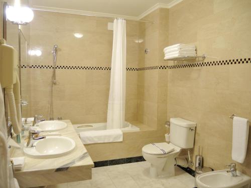 a bathroom with two sinks and a toilet and a tub at Grand Hotel Ukraine in Dnipro