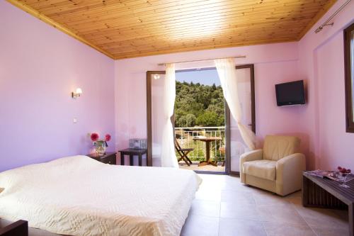 ein Schlafzimmer mit einem Bett und einem Stuhl sowie einem Balkon in der Unterkunft Il Viaggio Verde in Vasiliki