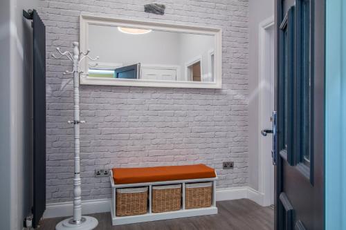 ein Badezimmer mit einem Spiegel und einer Bank vor einer Ziegelwand in der Unterkunft West Highland Apartments Milngavie - The Lomond in Milngavie