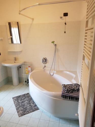 a white bathroom with a tub and a sink at Airport Orio Studio in Bergamo