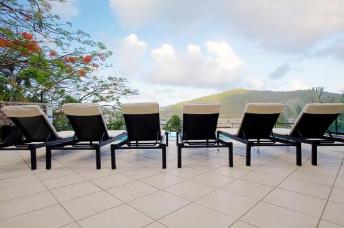 a group of chairs sitting on top of a patio at at Waterfront Whitsunday Retreat - Adults Only in Airlie Beach