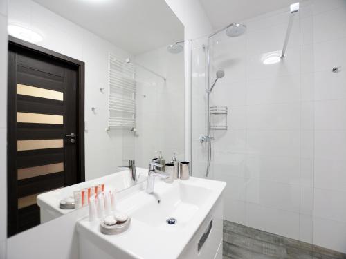 a white bathroom with a sink and a shower at Apartament Polanki Park-kryty basen in Kołobrzeg