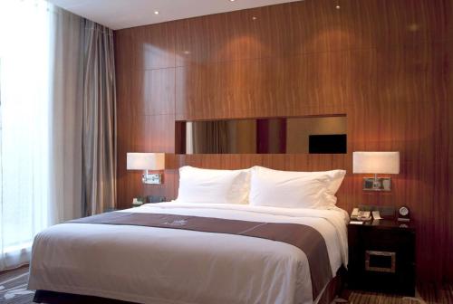 a bedroom with a large bed with a wooden wall at The Jade Boutique Hotel in Wuhan