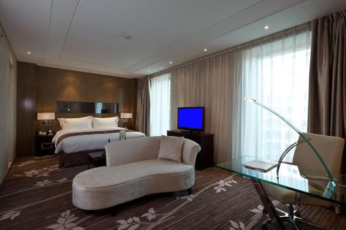 a hotel room with a bed and a couch and a television at The Jade Boutique Hotel in Wuhan
