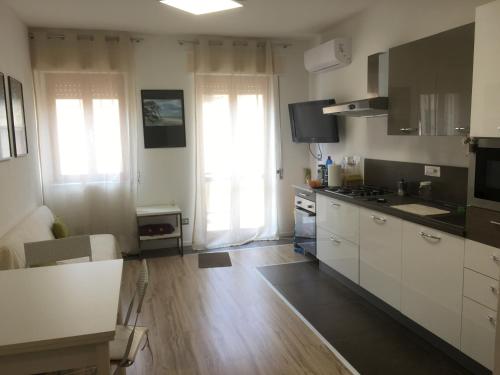 une cuisine avec des armoires blanches, du parquet et des fenêtres en bois dans l'établissement Alguer 46, à Alghero