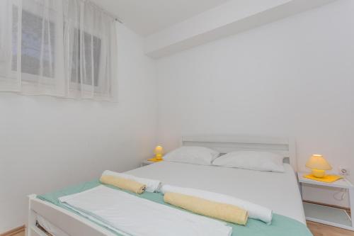 a white bedroom with a bed and two lamps at Apartment Dome in Biograd na Moru