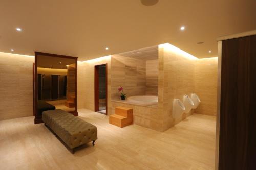 a bathroom with a tub and a bench in a room at FLC Luxury Resort Vinh Phuc in Hoằng Xá