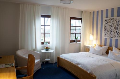 a hotel room with a bed and a desk and window at Landhaus Esperort in Ahrenshoop