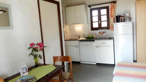 une cuisine avec une table et un réfrigérateur blanc dans l'établissement Rico Plage, à Figareto