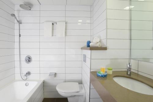 a white bathroom with a toilet and a sink at Leonardo Hotel Tiberias in Tiberias
