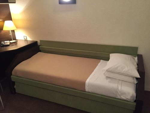 a bed in a hotel room with a desk and lamp at At Home Appart Hotel in Toulouse