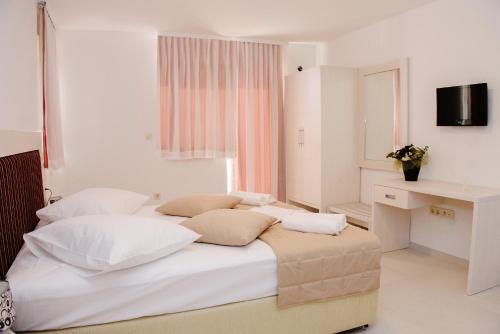 a white bedroom with a large bed with white pillows at Villa Palloma in Baška Voda