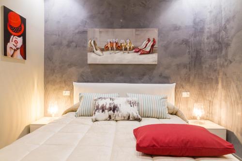 una camera da letto con un grande letto bianco con un cuscino rosso di Suite Bordonaro Apartments a Cefalù