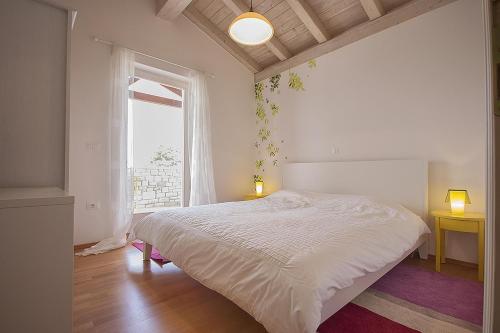 a bedroom with a white bed and a window at Villa Nunica in Radetići