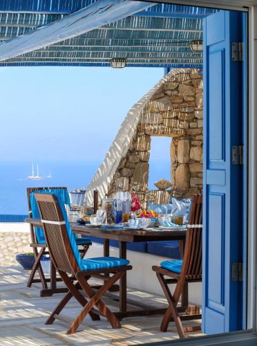 a table and chairs on the beach with the ocean in the background at Villa Celestia in Ornos