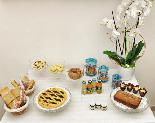 ein Tisch mit Kuchen und anderen Desserts und Blumen in der Unterkunft La Cattedrale in Ruvo di Puglia