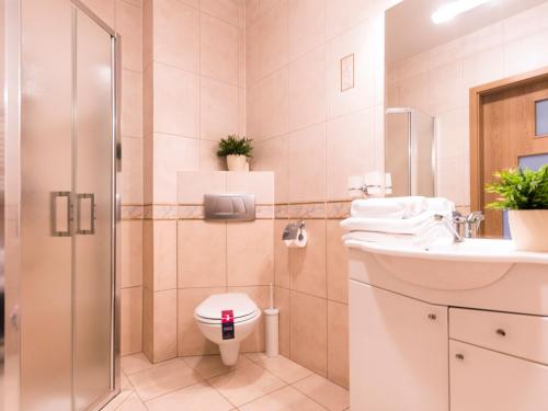 a bathroom with a toilet and a sink and a shower at VacationClub - Olymp Apartment 503 in Kołobrzeg